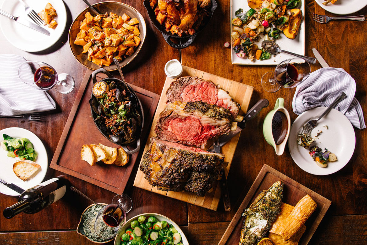 A spread of various dishes including carved steak and brussels sprouts